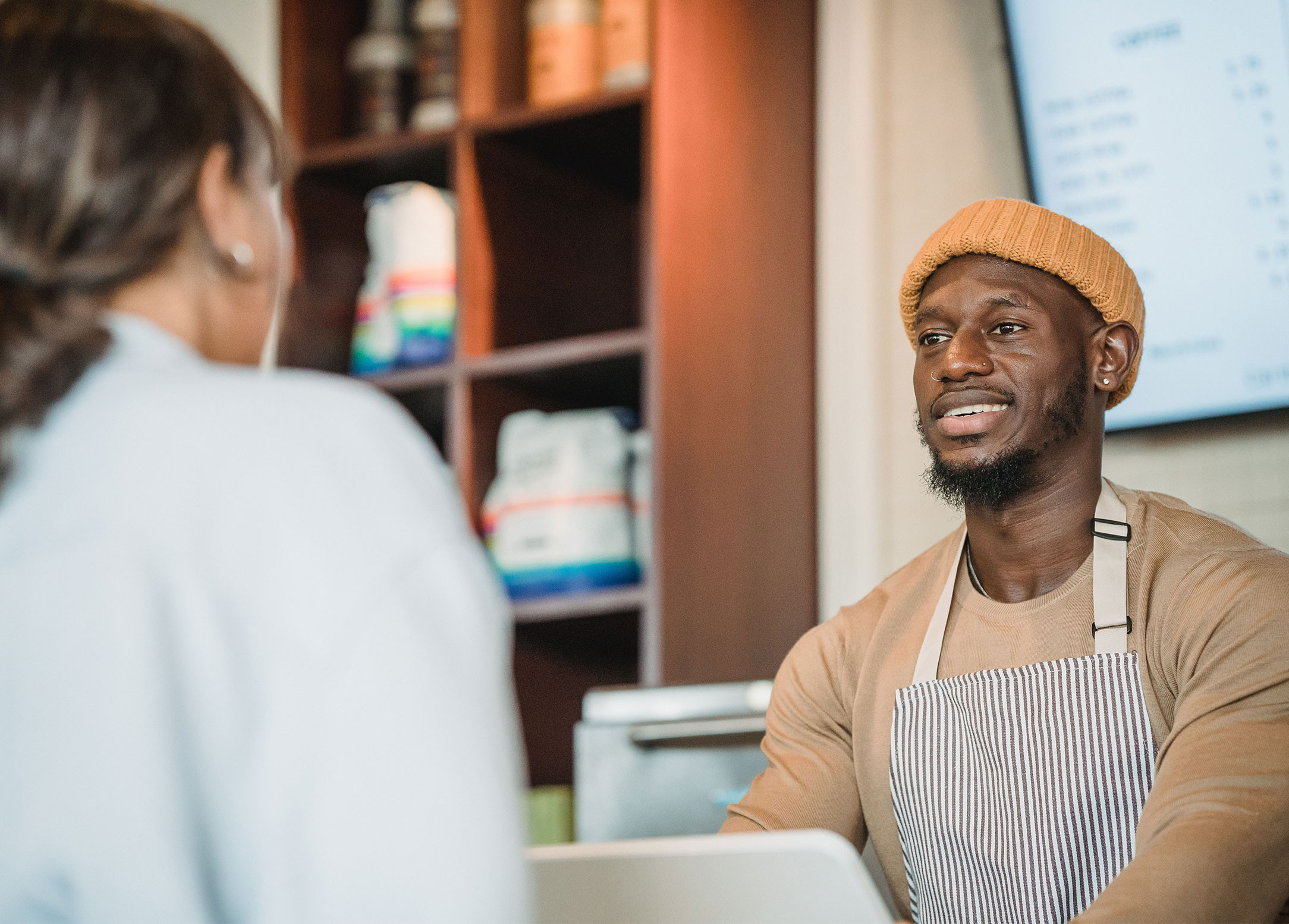 Man working at a register helping a customer. 