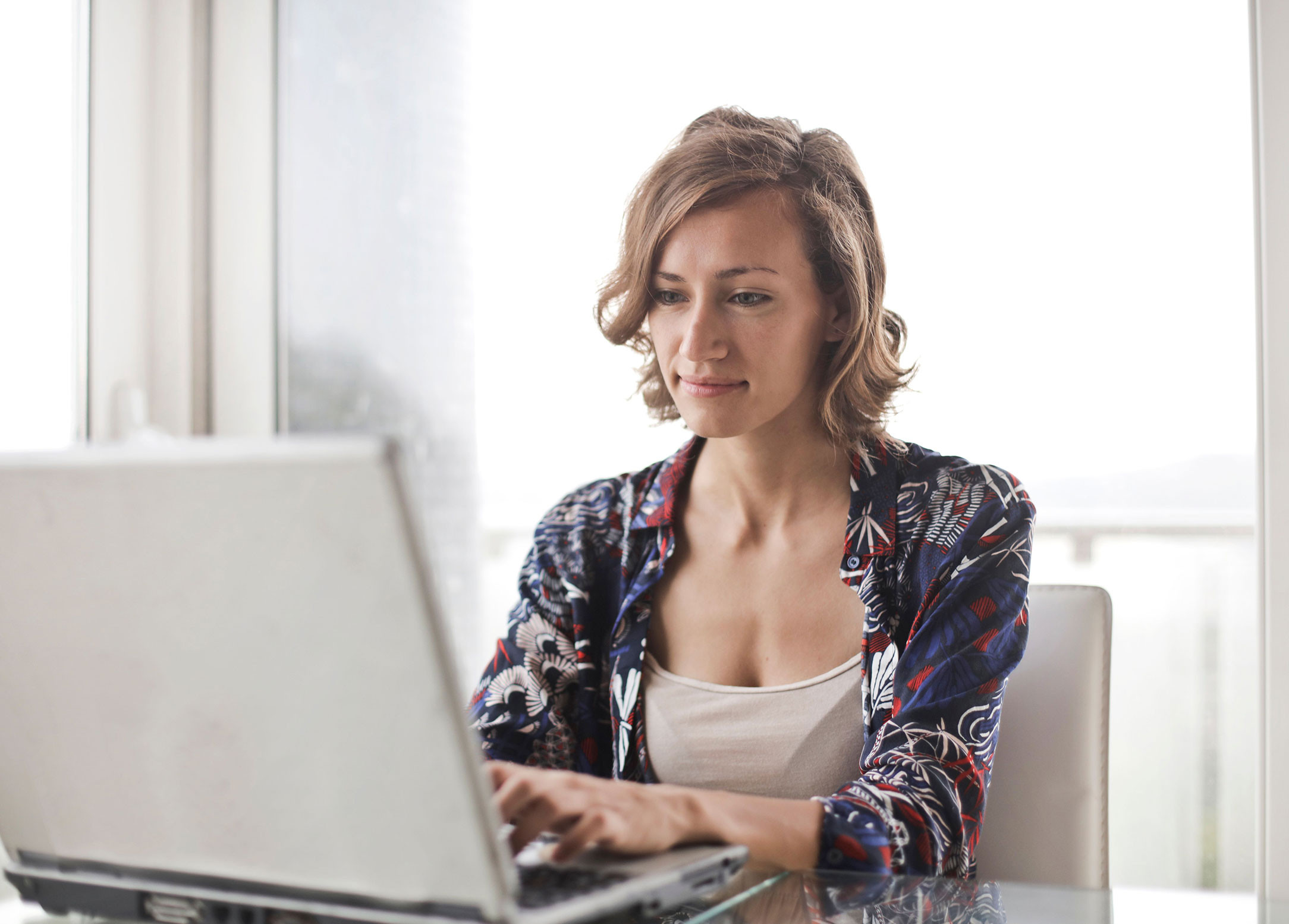 Woman sitting at desk with laptop clocking in using a time clock.